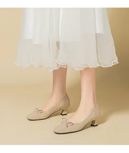 Macro view of elegant beige knit square-toe pumps featuring a bow and block heels