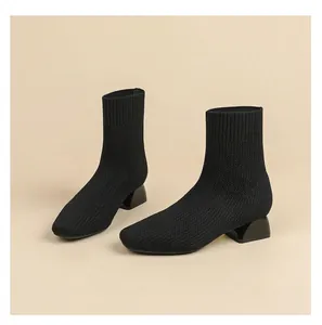 Détail de bottines en maille respirante noire avec talon bloc stable.