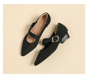 Macro view of black knit pointed-toe Mary Jane shoes featuring a silver buckle strap.