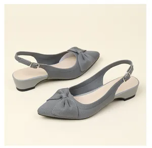 Detalle de sandalias slingback de punto gris con punta afilada y lazo decorativo.