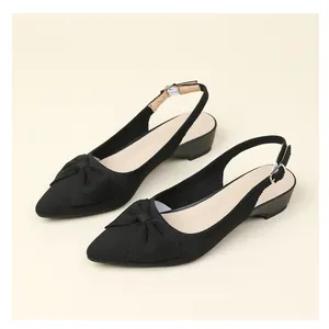 Detalle de los zapatos destalonados de punto negro con punta afilada y lazo.