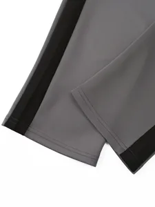Close-up of grey tracksuit pants cuff with black side stripe and stitching detail.
