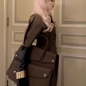 Vue de côté d'un élégant ensemble blazer marron à manches courtes avec un grand sac en cuir
