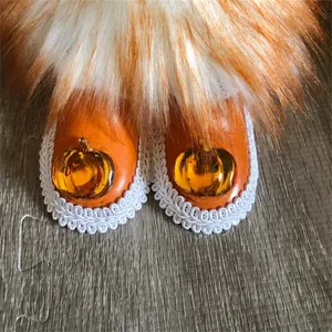 Detailed macro view of orange gnome doll boots with pumpkin decor and white lace trim
