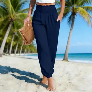 Model wearing navy blue loose beach joggers with elastic waist on a tropical beach