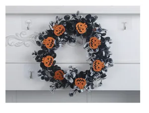 Close-up of Halloween wreath with black leaves and orange glitter pumpkins on wall