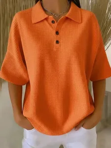 Close-up of bright orange waffle knit polo shirt for women with button detailing