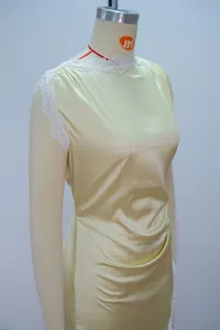 Detail mit eleganter weißer Spitze und gelbem Satinstoff eines figurbetonten Sommerkleides