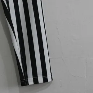 Close-up view of black and white vertical striped gym pants showing quality hem stitching.