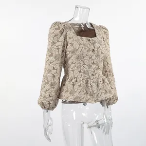 Dettaglio della trama jacquard floreale e dei bottoni dorati su questa camicetta