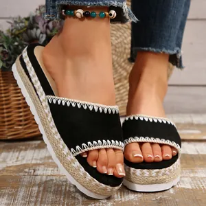 Detailopname van zwarte suède sleehaksandalen met een plateauzool van gevlochten touw