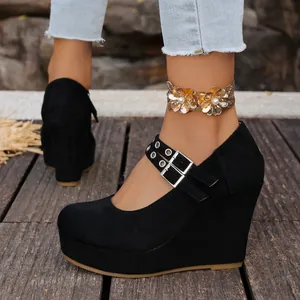 Detalle de zapatos de cuña en ante negro con correas de doble hebilla y ojales plata.