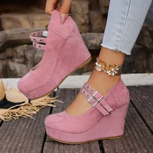 Detalle de cerca de zapatos de cuña con plataforma de gamuza rosa con hebillas metálicas