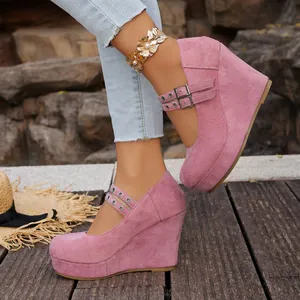 Detalle de zapatos de plataforma rosa con cuña y correas dobles con hebillas metálicas.