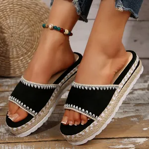 Close-up van zwarte espadrilles met plateauzolen en sleehakken voor dames.