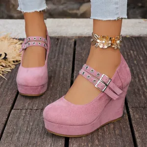 Detalle de zapatos de cuña en ante rosa con correas dobles ajustables y hebillas.