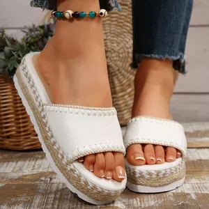 Gedetailleerd zicht op witte plateau slippers met jute geweven zool en borduurwerk