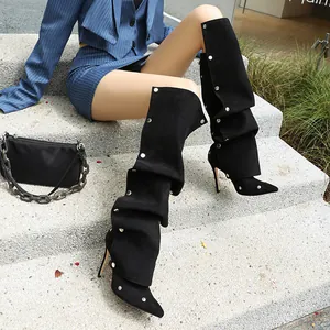 Detailansicht modischer schwarzer Slouch-Stiefel mit silbernen Nieten und spitzer Kappe