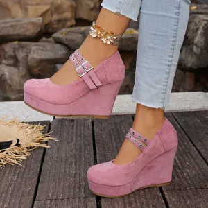 Detalle de elegantes zapatos de plataforma con cuña rosa y correas de hebilla doble.