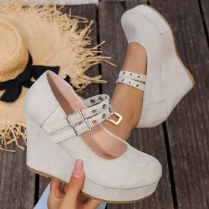 Primer plano de zapatos de cuña en ante gris con modernas hebillas de metal en corazón.