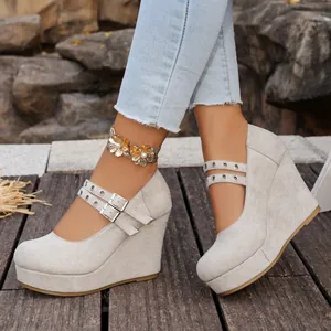 Detalle de zapatos de cuña de ante gris claro con correas de doble hebilla en pie.