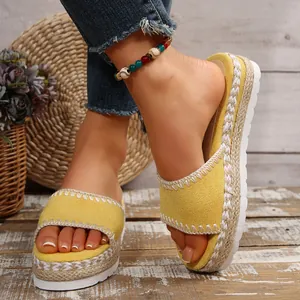 Detail van gele sleehak sandalen met stiksels en gevlochten hennep espadrille zolen.