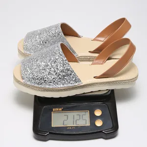 Close-up detail showing the lightweight weight of a silver glitter flat peep-toe sandal