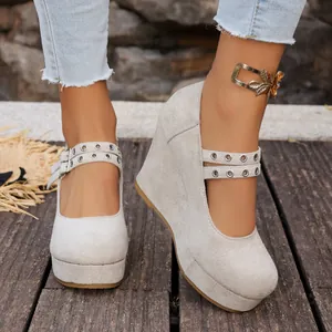 Detalle de zapatos de cuña de ante beige con correas dobles de ojales y hebilla dorada chic.