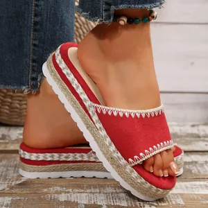 Detailweergave van rode plateau-sandalen met sleehak, jute vlechtwerk en witte stiksels