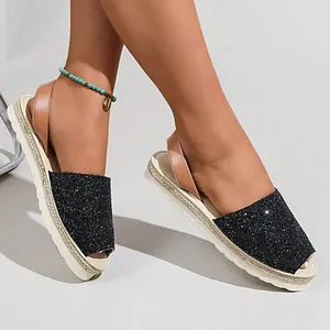 Close-up of black glitter peep-toe sandals with tan ankle strap and espadrille sole
