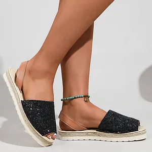 Detail of shiny black sequined open-toe sandals with comfortable brown heel straps.