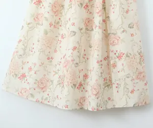 Close-up of floral print dress hem showing detailed pink peony patterns on cream fabric.
