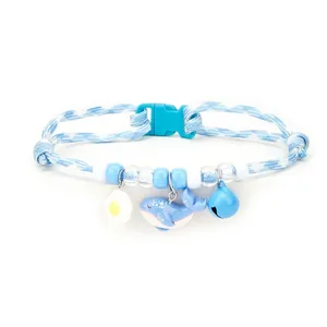 Detailed view of blue pet collar featuring cartoon whale, egg charms and a blue bell
