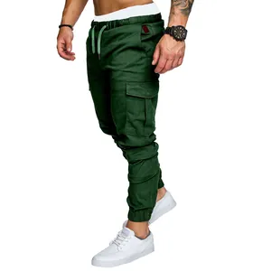Men's dark green multi-pocket cargo pants styled with white leather sneakers on white background