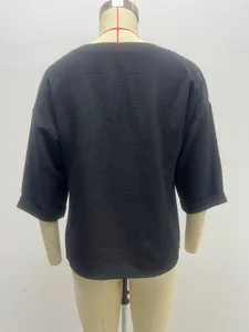 Back view of a minimalist black three-quarter sleeve blouse with textured fabric on mannequin