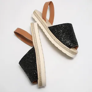 Detailed view of shiny black glitter peep-toe sandals with a rope-textured platform sole.