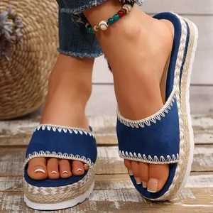 Detail van blauwe suède plateausandalen met gevlochten touwzolen en witte stiksels.
