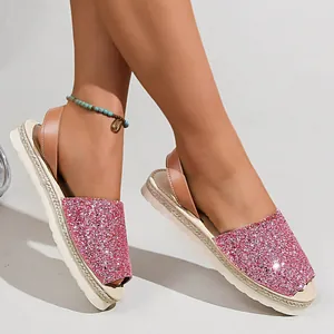 Close-up view of shiny pink glitter peep-toe flat sandals with a braided jute sole