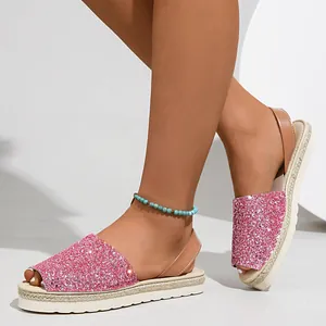 Close-up of stylish pink sequin peep-toe espadrille flat sandals shown on model feet