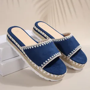 Detail van blauwe suède sleehak slippers met een gevlochten touwplatform zool