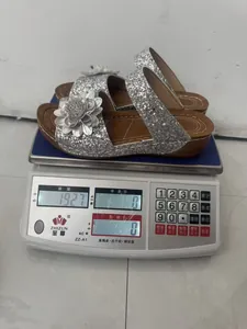 Lightweight silver glitter wedge sandals with floral detail on digital weight scale