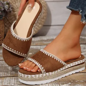 Detailopname van bruine suède wedge sandalen met een platform van gevlochten jute touw.