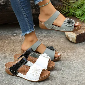 Detail shot of wedge open-toe sandals with elegant flower decor and croc-pattern strap