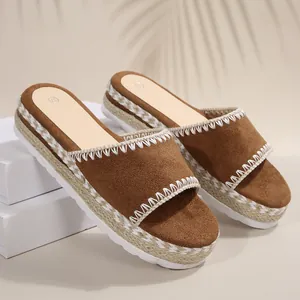 Detailweergave van bruine suède plateausandalen met touwvlechten en borduurwerk.