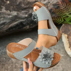 Detailed view of grey floral wedge sandals with decorative white stitching and open-toe design.