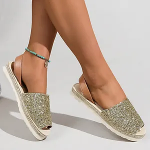Close-up detail of women's sparkling gold glitter peep-toe espadrille flat sandals
