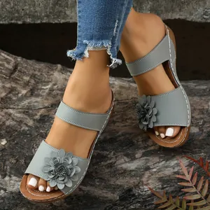 Macro view of women's grey wedge sandals featuring a 3D flower decoration and open toe design
