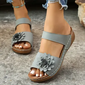 Macro view of gray women's wedge sandals featuring a decorative flower and stitching.