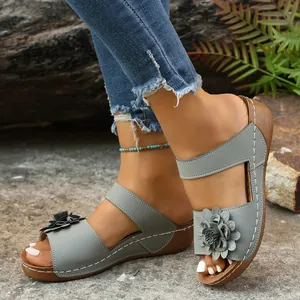 Close-up view of grey wedge sandals with floral detail on a natural outdoor background