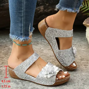 Side view of silver glittery wedge sandals with floral accent and heel height info